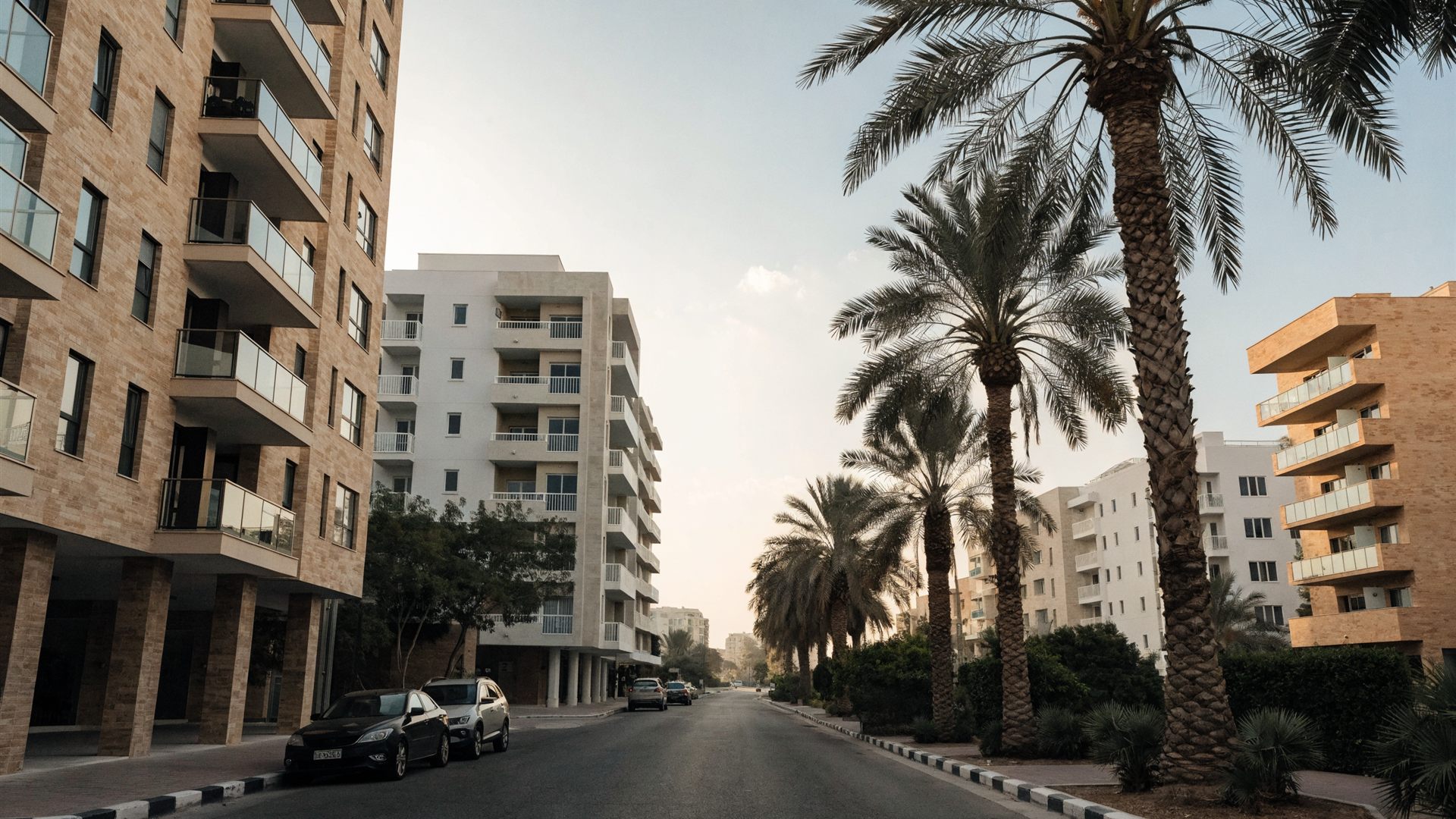 A residential street in Dubai lined with apartment buildings and palms